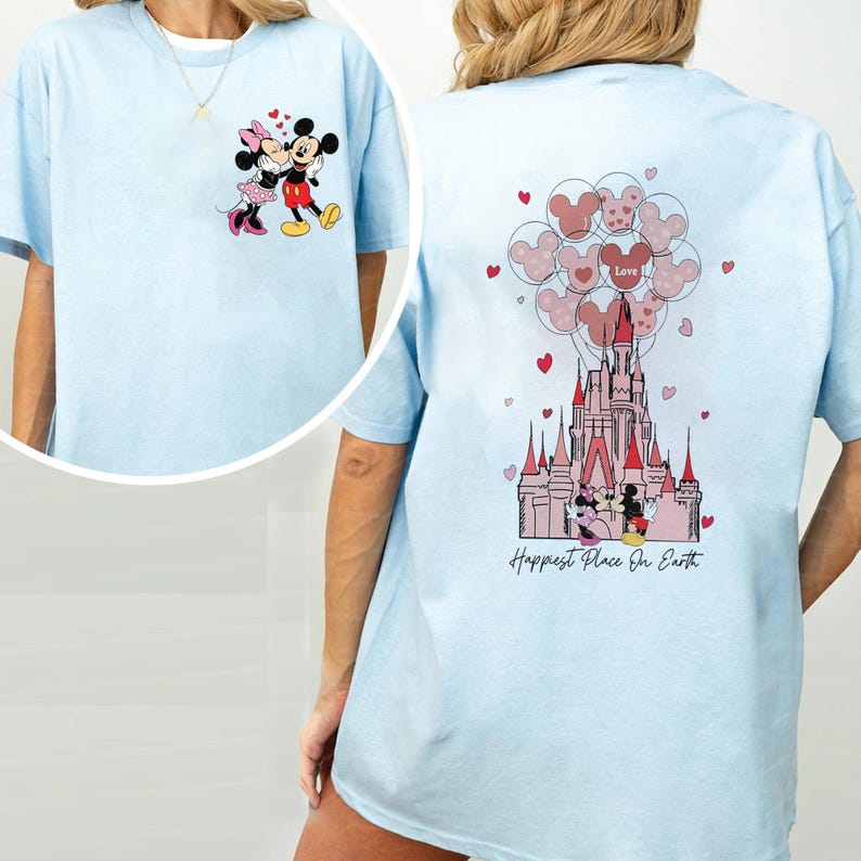 May include: Light blue t-shirt featuring Mickey and Minnie Mouse. The front has a graphic of the couple, while the back displays a castle with Mickey Mouse balloons and the text "Happiest Place On Earth."