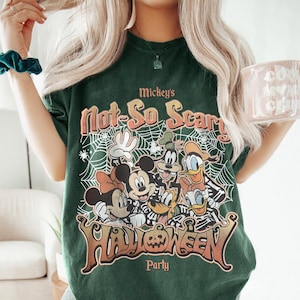 Puede incluir: Camiseta verde oscuro con un dise&ntilde;o de Halloween de Mickey Mouse, Minnie Mouse, Goofy, Donald Duck y Pluto. El texto en la camiseta dice "Mickey's Not-So-Scary Halloween Party."