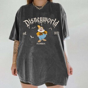Op de afbeelding: Donkergrijs T-shirt met een Disneyworld-afbeelding. Het ontwerp bevat de tekst "Disneyworld", het jaar "1971" en een cartoonfiguur. Het woord "Florida" staat ook op het shirt.