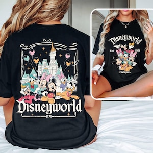 Puede incluir: Camiseta negra con un gr&aacute;fico de Mickey Mouse y sus amigos frente al Castillo de Cenicienta. El texto "Disneyworld - Est. 1971 - Florida" est&aacute; impreso en la camiseta.