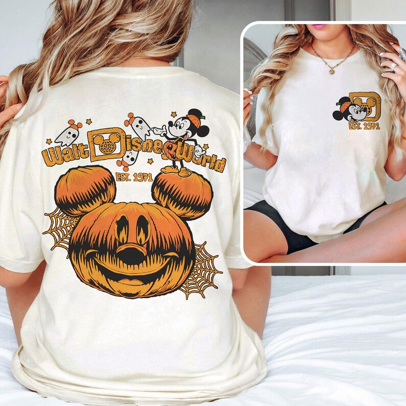 May include: Cream-colored t-shirt featuring a Halloween-themed Walt Disney World design. The design includes a smiling jack-o'-lantern, Mickey Mouse, ghosts, and the text "Walt Disney World" and "Est. 1971" in orange.
