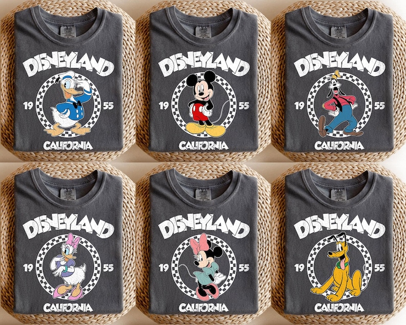 K&ouml;nnte beinhalten: Sechs anthrazitfarbene T-Shirts mit Disney-Figuren. Jedes Shirt zeigt "DISNEYLAND" in Wei&szlig;, mit einer Charakterillustration in einem Kreis, dem Jahr "1955" und "CALIFORNIA". Zu den Charakteren geh&ouml;ren Donald Duck, Mickey Mouse, Goofy, Daisy Duck, Minnie Mouse und Pluto.