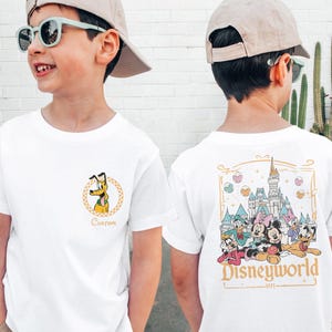 May include: White t-shirt with a cartoon image of Pluto on the front and a graphic of Mickey Mouse and friends in front of Cinderella's Castle on the back. The back graphic also includes the text "Disneyworld - 1971 - ".