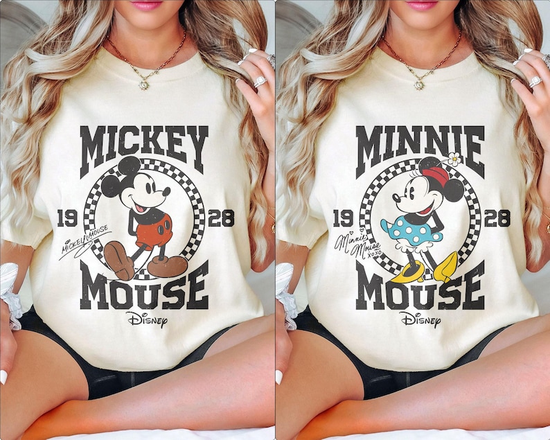 Op de afbeelding: Twee cr&egrave;mekleurige T-shirts met een vintage Mickey Mouse en Minnie Mouse afbeelding. De shirts hebben een zwart-wit geblokte cirkel met de naam van het personage en de jaren 1928 en 1928. De shirts hebben ook het Disney-logo.
