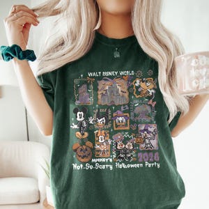 May include: Dark green t-shirt featuring a graphic design for Mickey's Not-So-Scary Halloween Party 2026 at Walt Disney World. The design includes images of Mickey Mouse, Donald Duck, and other Disney characters in Halloween costumes.