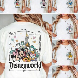 May include: Cream-coloured t-shirts featuring Disney characters. The front of the shirts display Mickey Mouse, Minnie Mouse, Donald Duck, Daisy Duck, Goofy, and Pluto with a castle and the word "Custom". The back of the shirt has a large graphic with Disney characters and the text "Disneyworld 1971".