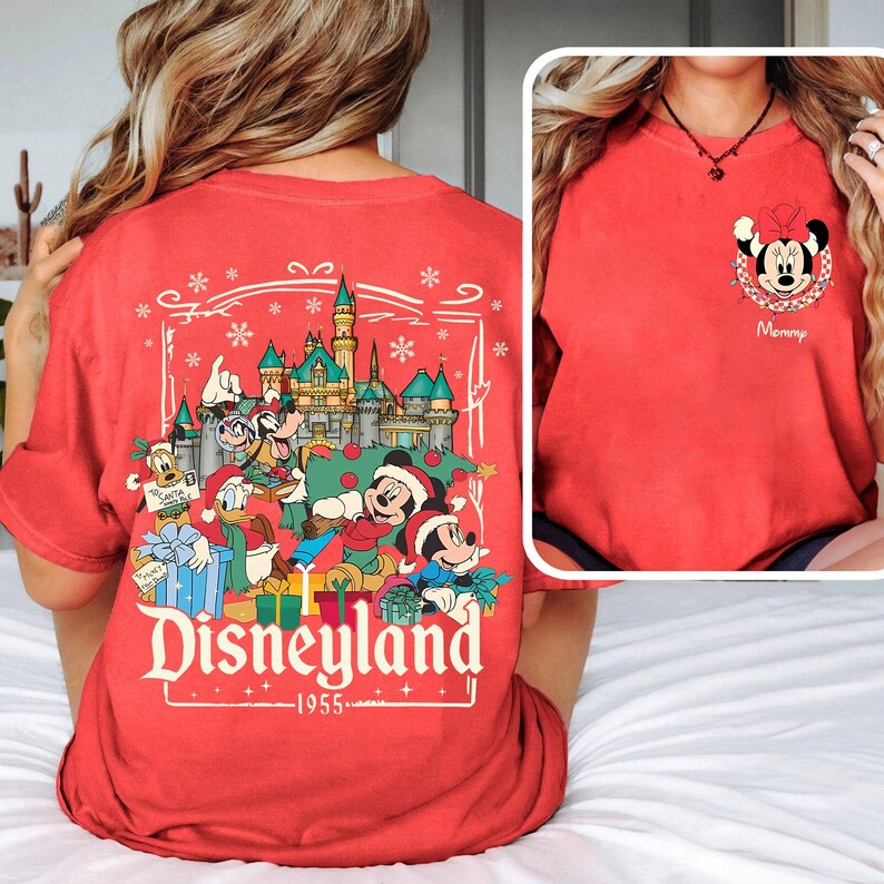 May include: Red t-shirt featuring a Disneyland graphic with Mickey Mouse, Donald Duck, and Goofy in Santa hats. The back of the shirt displays a Disneyland castle and characters. A smaller image shows Minnie Mouse with the word "Mommy".