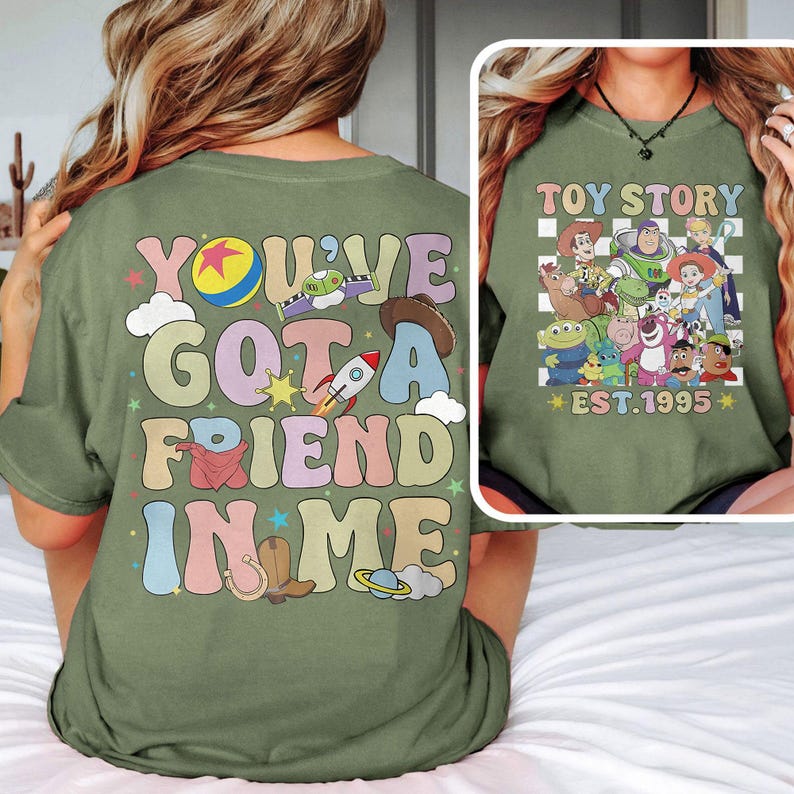 May include: Green t-shirt with a retro-style graphic that says "You've Got a Friend in Me" with a cartoon image of Woody's hat, a rocket, a horseshoe, and a planet. The back of the shirt has a checkered pattern with a group of Toy Story characters and the text "Toy Story Est. 1995".