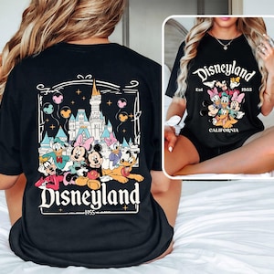 May include: Black t-shirt with a graphic print of Mickey Mouse and friends in front of the Disneyland castle. The text "Disneyland Est. 1955 California" is printed on the shirt.