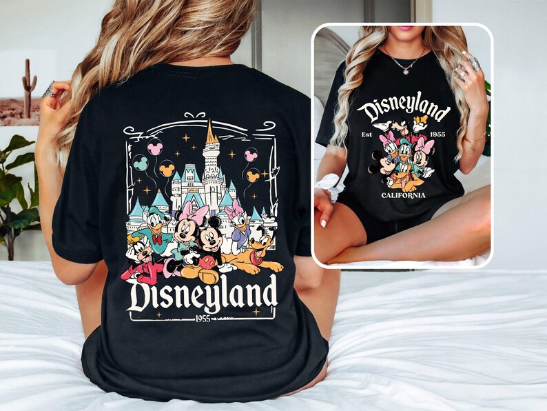 May include: Black t-shirt with a graphic print of Mickey Mouse and friends in front of the Disneyland castle. The text "Disneyland Est. 1955 California" is printed on the shirt.