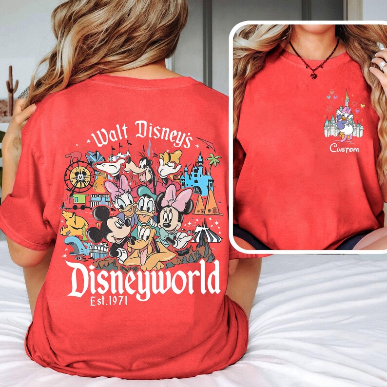 May include: Red t-shirt featuring a Disney World graphic on the back with Mickey, Minnie, Donald, Daisy, and Goofy. The front has a smaller graphic of a castle and the word "Custom". The shirt is a comfortable, casual style.