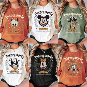 May include: Collection of six t-shirts with the text "Disneyworld" and various character designs. Each shirt features a different color, including orange, white, black, and green. The shirts have the text "Est. 1971" and "Spookiest Place on Earth".