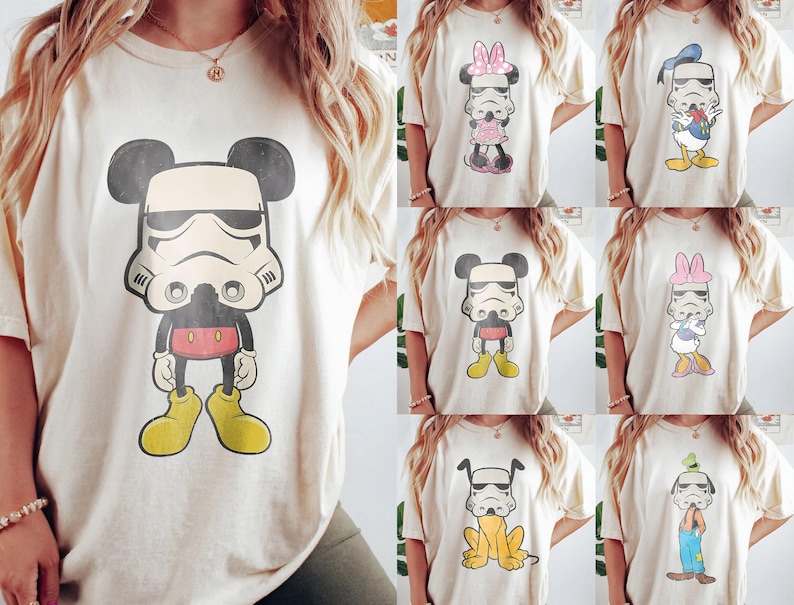 May include: Cream-colored t-shirts featuring cartoon characters in Stormtrooper helmets. Designs include Mickey Mouse, Minnie Mouse, Donald Duck, and Goofy. Each character is depicted in their signature attire, with yellow, red, and blue accents.