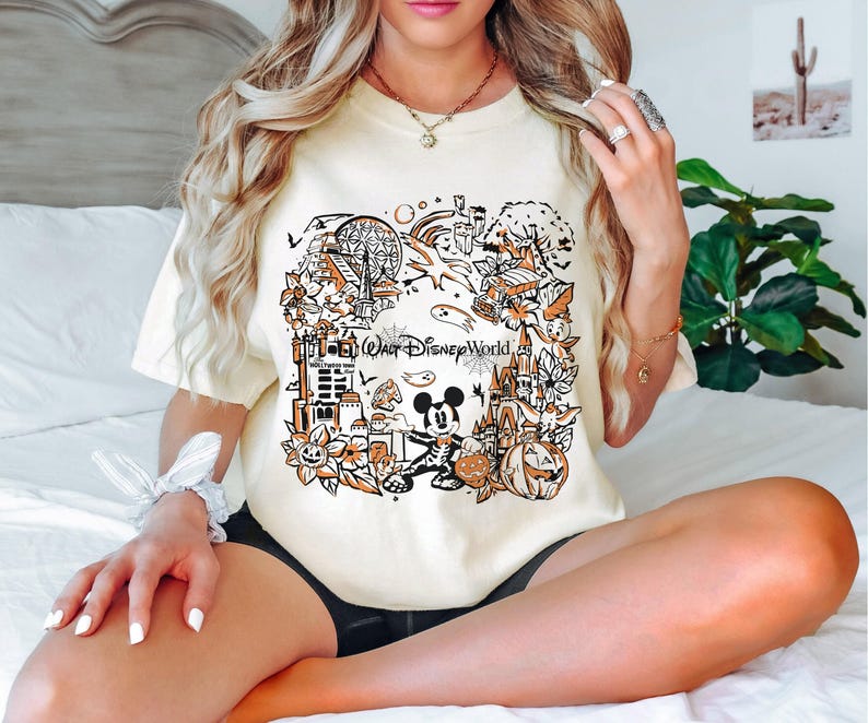 May include: A white t-shirt with a black and orange graphic print of Mickey Mouse and Halloween themed imagery. The graphic includes the text "Walt Disney World".