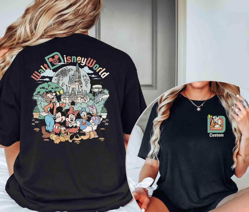 Puede incluir: Camiseta negra con un gr&aacute;fico colorido de personajes de Disney y el texto "Walt Disney World". El dise&ntilde;o incluye a Mickey Mouse, Minnie Mouse, el Pato Donald y Goofy frente a un castillo. Una camiseta m&aacute;s peque&ntilde;a muestra un dise&ntilde;o personalizado.