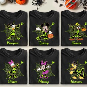 May include: Six black t-shirts with Halloween-themed designs. Each shirt features a different Disney character in a skeleton costume, surrounded by a spider web. The shirts are labeled "Brother", "Daddy", "Grandpa", "Sister", "Mommy", and "Grandma".