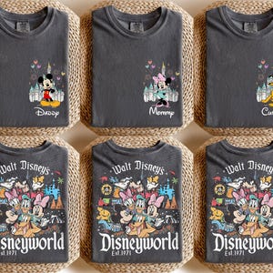 May include: Six dark gray t-shirts with Disney character designs. Three shirts feature Mickey, Minnie, and Pluto with text like "Daddy", "Mommy", and "Custom". The other three shirts display a colorful Disney World graphic with "Walt Disney's Disneyworld Est. 1971".