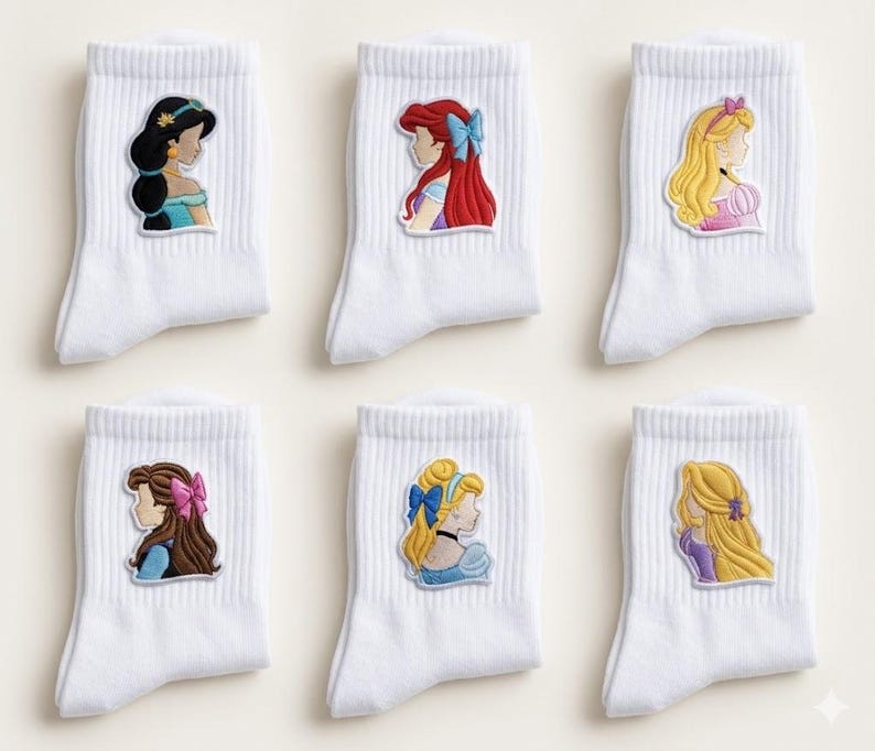 May include: Six pairs of white ankle socks, each with a princess design. The embroidered patches show the princesses in profile, with their iconic hairstyles and outfits. The socks are made of a ribbed knit material.