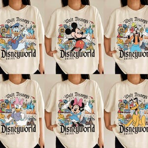 May include: Cream-colored t-shirts featuring various Disney characters like Mickey Mouse, Donald Duck, and Goofy. Each shirt has a colorful graphic of Disney World with the text "Walt Disney's Disneyworld Est. 1971."