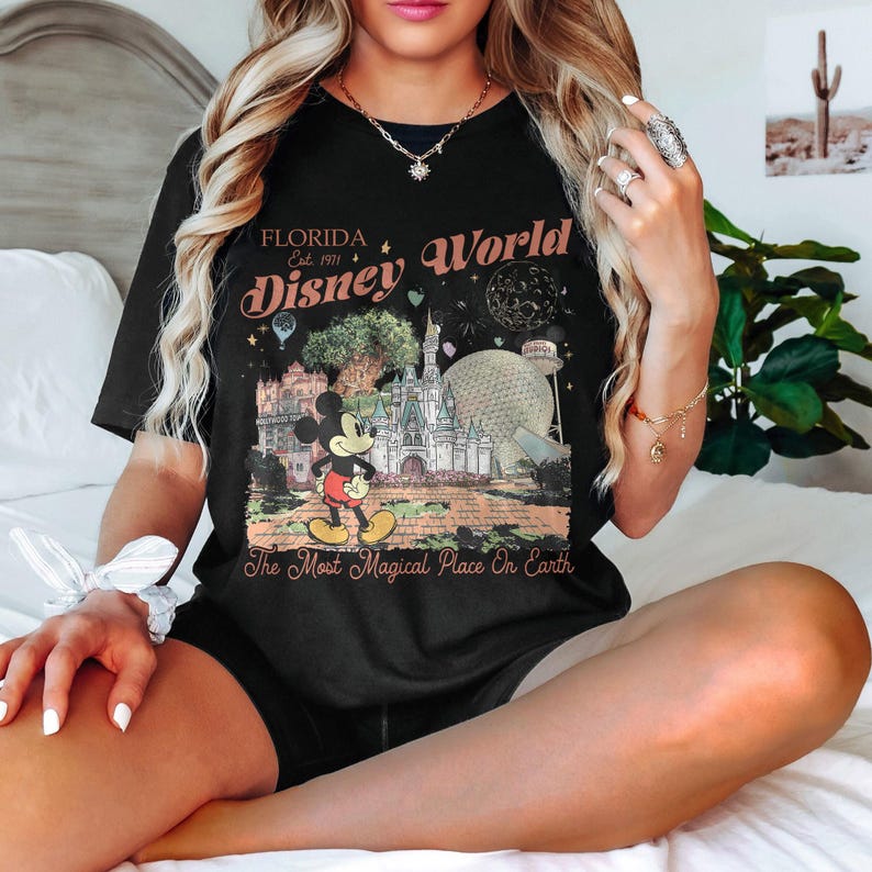 May include: Black t-shirt featuring a colorful graphic of Disney World in Florida. The design includes Mickey Mouse, a castle, and the text "Florida Disney World Est. 1971" and "The Most Magical Place On Earth."