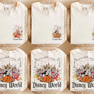 May include: Off-white t-shirts with Disney World graphics. Some shirts feature a castle and characters with the text "Custom Name". Other shirts have a larger design with Mickey Mouse, pumpkins, and the text "Disney World 1971".
