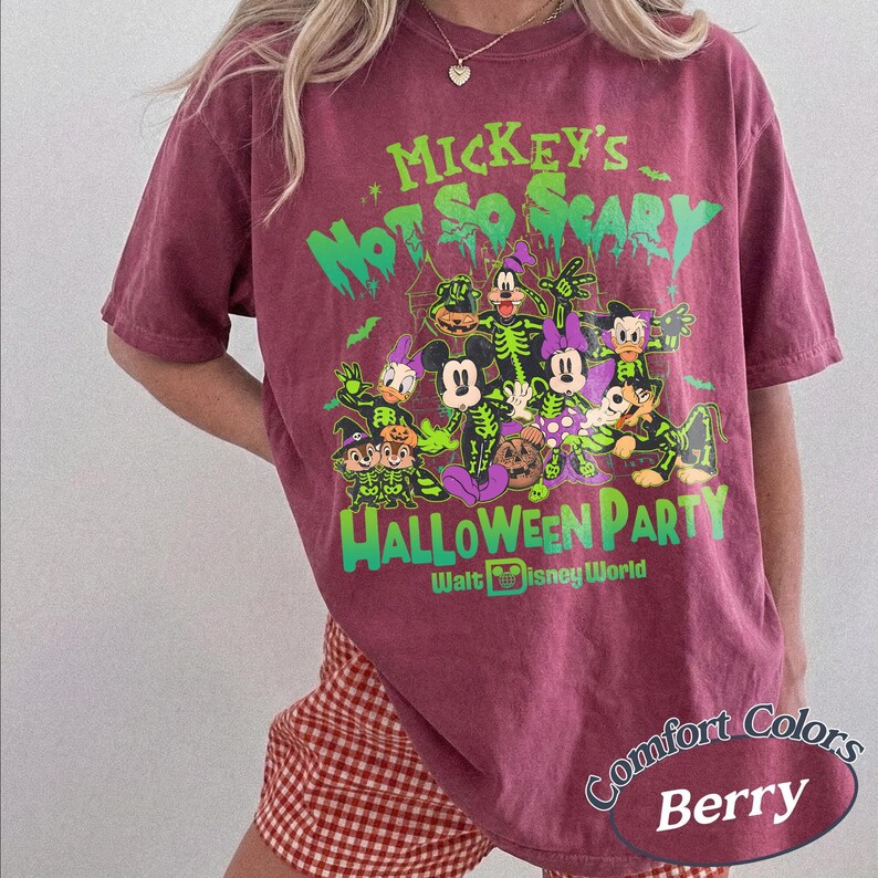 Op de afbeelding: Bessenkleurig T-shirt met een Halloween-thema Disney-afbeelding. Het ontwerp bevat de tekst "Mickey's Not So Scary Halloween Party" en "Walt Disney World" in groen en paars. Het shirt is van het merk Comfort Colors.