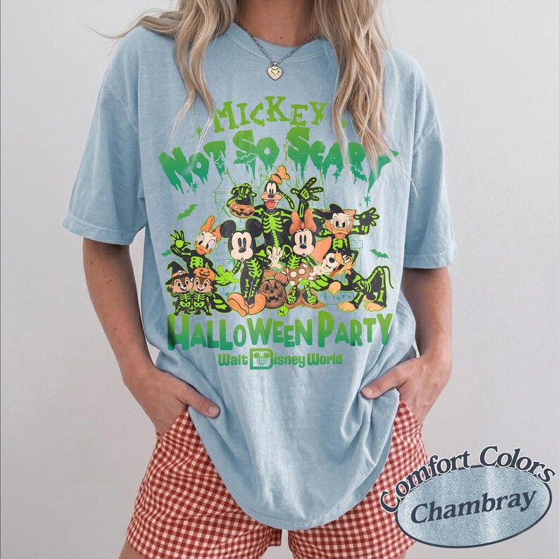 K&ouml;nnte beinhalten: Hellblaues T-Shirt mit einem Halloween-Motiv mit Disney-Figuren in Skelett-Kost&uuml;men. Der gr&uuml;ne Text lautet "Mickey Not So Scary Halloween Party". Das Shirt ist ein Comfort Colors Chambray.