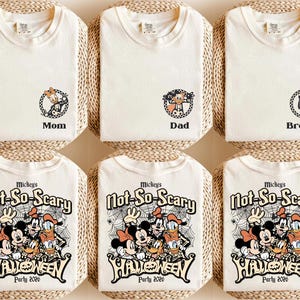 May include: Off-white t-shirts with Halloween-themed graphics. Some shirts have character designs with the words "Mom", "Dad", and "Brother". Other shirts feature Mickey Mouse and friends with the text "Mickey's Not-So-Scary Halloween Party 2026".
