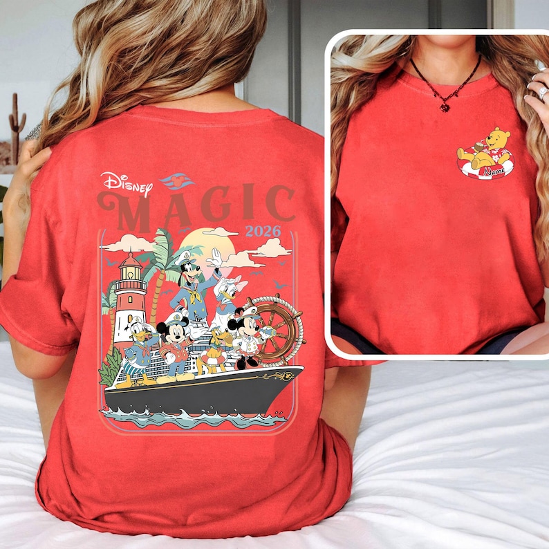 May include: Red t-shirt with a Disney cruise design. The back of the shirt shows the words "Disney Magic 2026" above a graphic of Disney characters on a ship. The front has a small graphic of Winnie the Pooh on a float.
