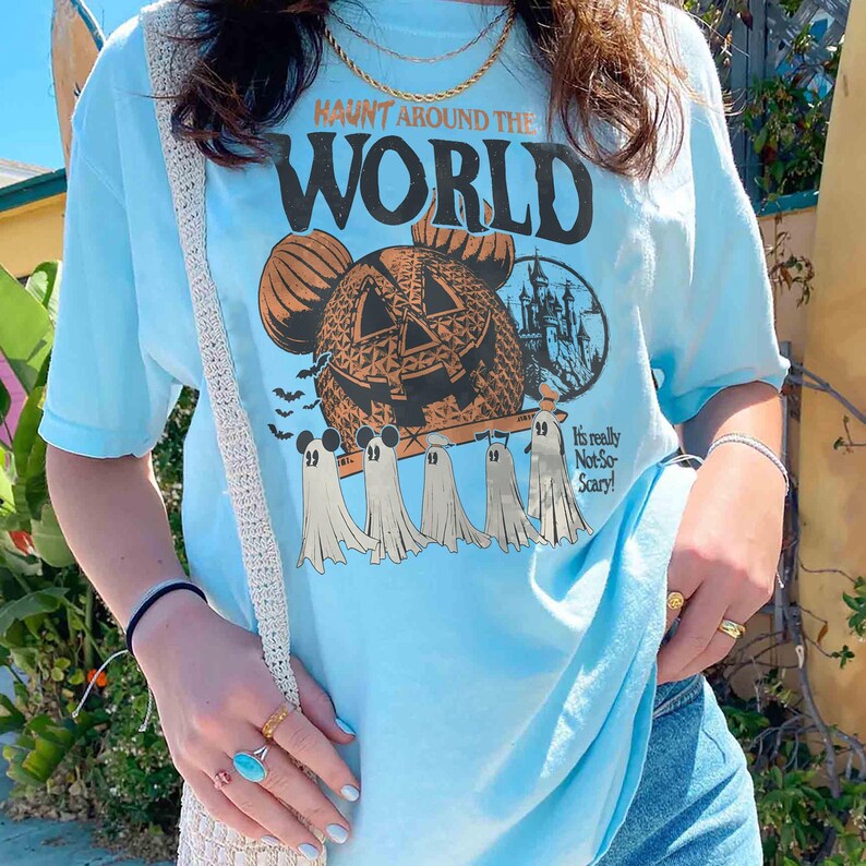 May include: Light blue t-shirt with a graphic of a jack-o'-lantern Mickey Mouse head and the text "Haunt Around the World".  The graphic also includes a castle and ghosts.