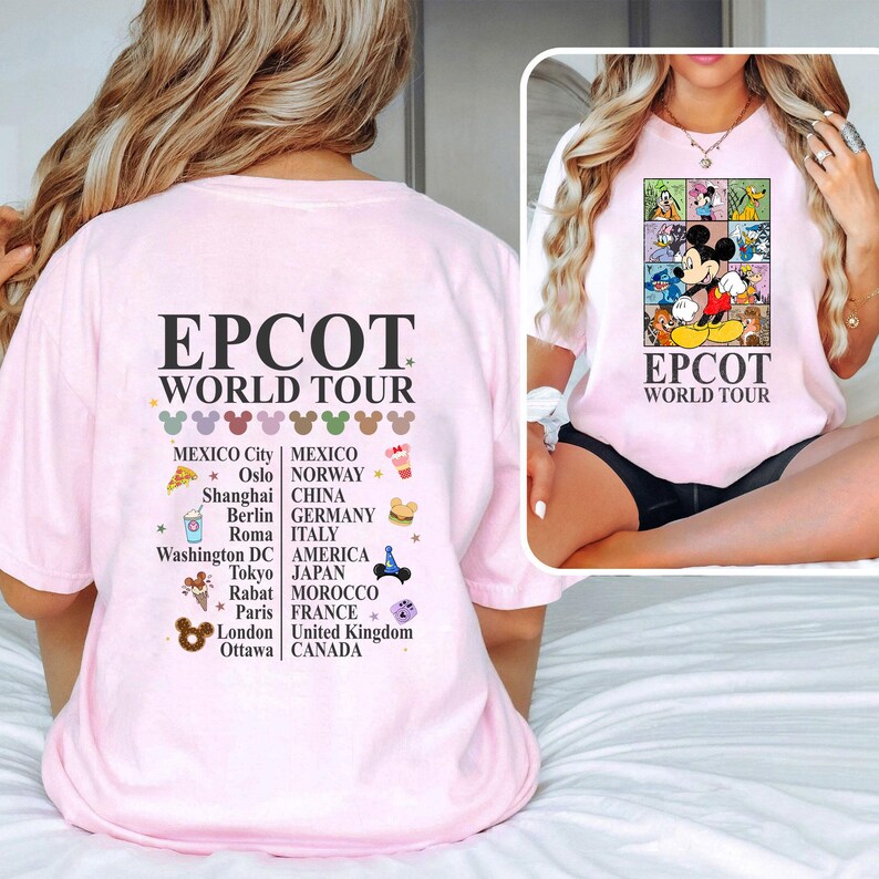 Pode incluir: Camiseta rosa com um gr&aacute;fico de Mickey Mouse e outros personagens da Disney. O texto "EPCOT World Tour" est&aacute; impresso na camiseta. A parte de tr&aacute;s da camiseta tem uma lista de pa&iacute;ses e cidades com o texto "EPCOT World Tour" impresso acima da lista.