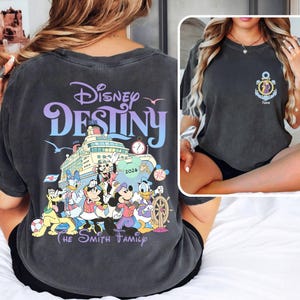 May include: Dark gray t-shirt featuring the words "Disney Destiny" in purple and blue, with a cruise ship graphic and Disney characters. The shirt also includes "The Smith Family" text.