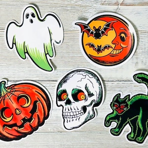 May include: A collection of Halloween-themed stickers. Includes a white ghost with green accents, a smiling moon with bats, a jack-o'-lantern, a skull, and a black cat with glowing green outlines.