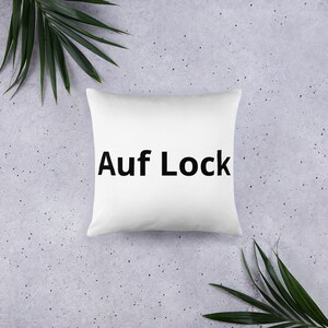 May include: White pillow with black text that reads "Auf Lock".
