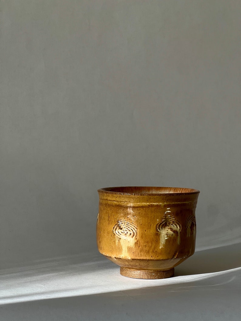 May include: A brown ceramic bowl with a textured, swirling design. The bowl has a wide base and a rounded shape.