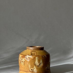 May include: A small, yellow ceramic bowl with a textured, swirling design. The bowl has a slightly rounded shape and a wide rim.