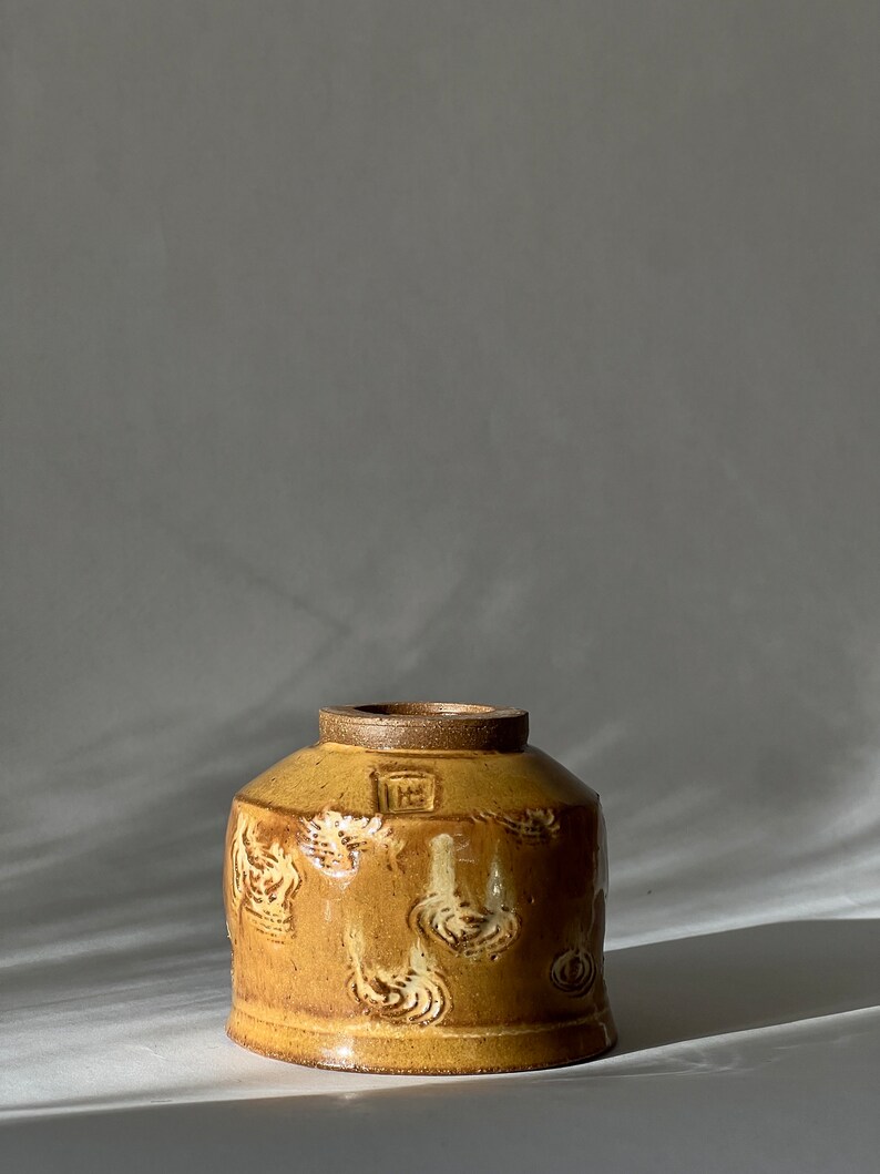 May include: A small, yellow ceramic bowl with a textured, swirling design. The bowl has a slightly rounded shape and a wide rim.