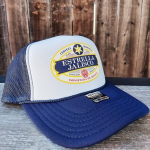 May include: A white and blue trucker hat with a yellow and red logo that says "Estrella Jalisco" and "Importada de Mexico".