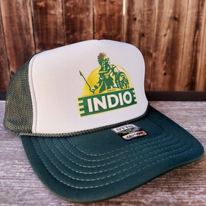 May include: A green and white trucker hat with a logo of a green warrior holding a spear and shield. The logo says "Cerveza Indio" in green and white letters.