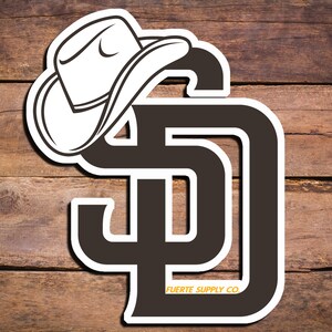 May include: A black and white sticker with a cowboy hat on top of the letters "SD" and the text "FUERTE SUPPLY CO."