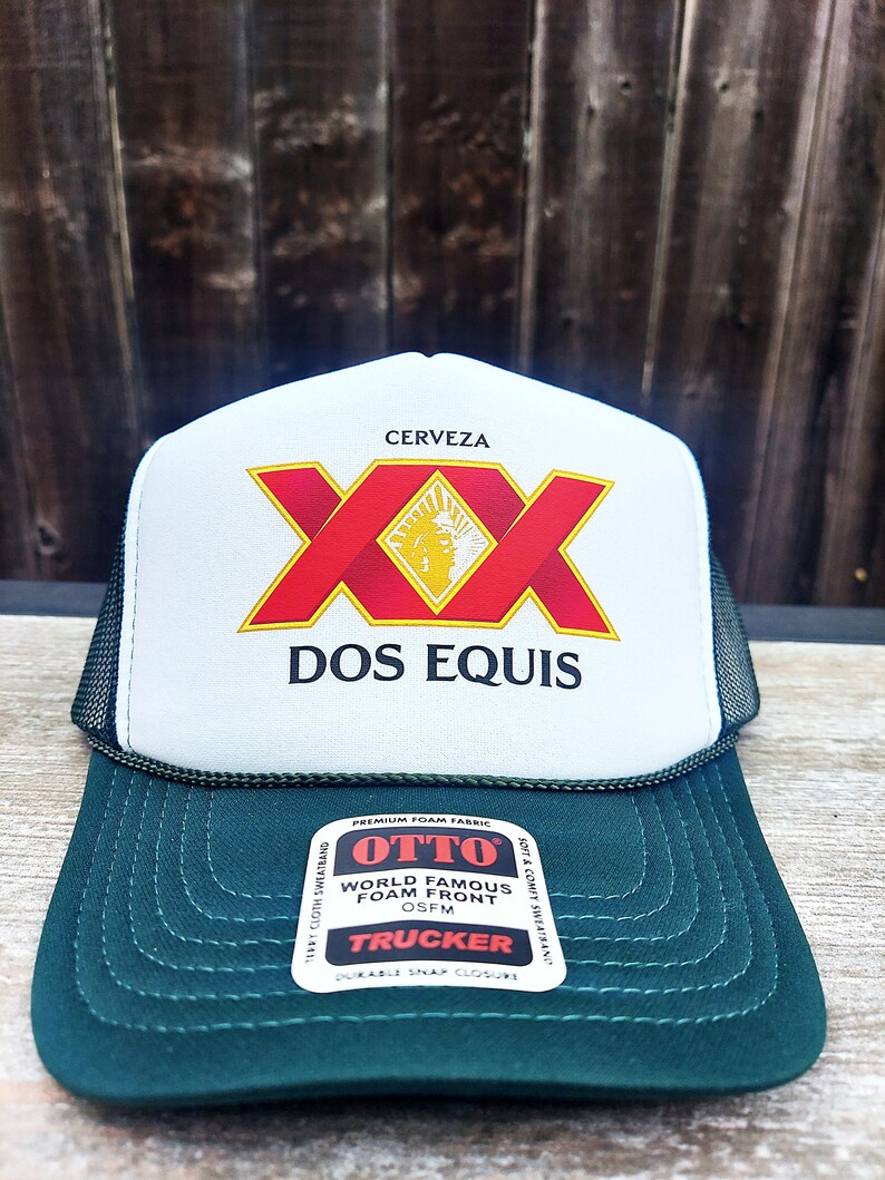 May include: A white and green trucker hat with a red and yellow "Dos Equis" logo. The hat has a mesh back and a foam front.