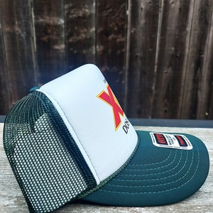 May include: A green and white trucker hat with a red and yellow logo that says "Dos Equis" on the front. The hat has a mesh back and a green brim.