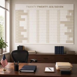 May include: A large wall calendar titled TWENTY TWENTY-SIX/SEVEN featuring a grid layout with months listed from October to September. The design uses a neutral color palette of white and beige, with horizontal bars highlighting specific date ranges.