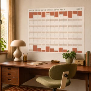 May include: A large 2027 wall calendar with a minimalist design, featuring the text YOUR YEAR. YOUR SPACE. YOUR PLAN. The calendar displays a grid layout with alternating terracotta and cream-colored blocks for each month of the year.