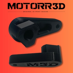 Könnte beinhalten: Zwei schwarze 3D-gedruckte Teile werden vor einem orange-roten Farbverlaufshintergrund gezeigt. Das obere Teil hat eine zylindrische Öffnung und einen rechteckigen Block. Das untere Teil trägt den Text "M3D". Der Text "MOTORR3D" befindet sich oben.