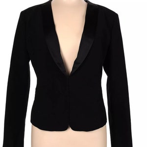 May include: A black blazer with a satin lapel. The blazer has a classic, tailored design with a V-neckline and long sleeves. The garment is displayed on a mannequin.