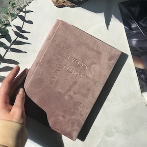 May include: A dusty rose velvet journal with the name "Evelyn Flores" embossed on the front cover.