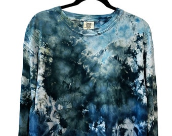 May include: A long-sleeved tie-dye shirt in shades of blue and green. The shirt has a crew neck and a relaxed fit. The shirt is made of a soft, comfortable fabric.