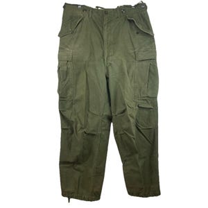 May include: Olive green cargo pants with multiple pockets and a button and zipper closure. The pants have a drawstring at the waist and at the ankles. The pants are made of a durable fabric.