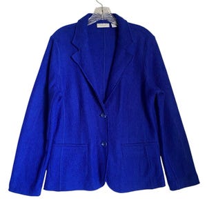 May include: A vibrant blue blazer with a two-button closure and two front pockets. The jacket is hanging on a hanger against a white background. The blazer has a classic lapel design and is made of a textured fabric.